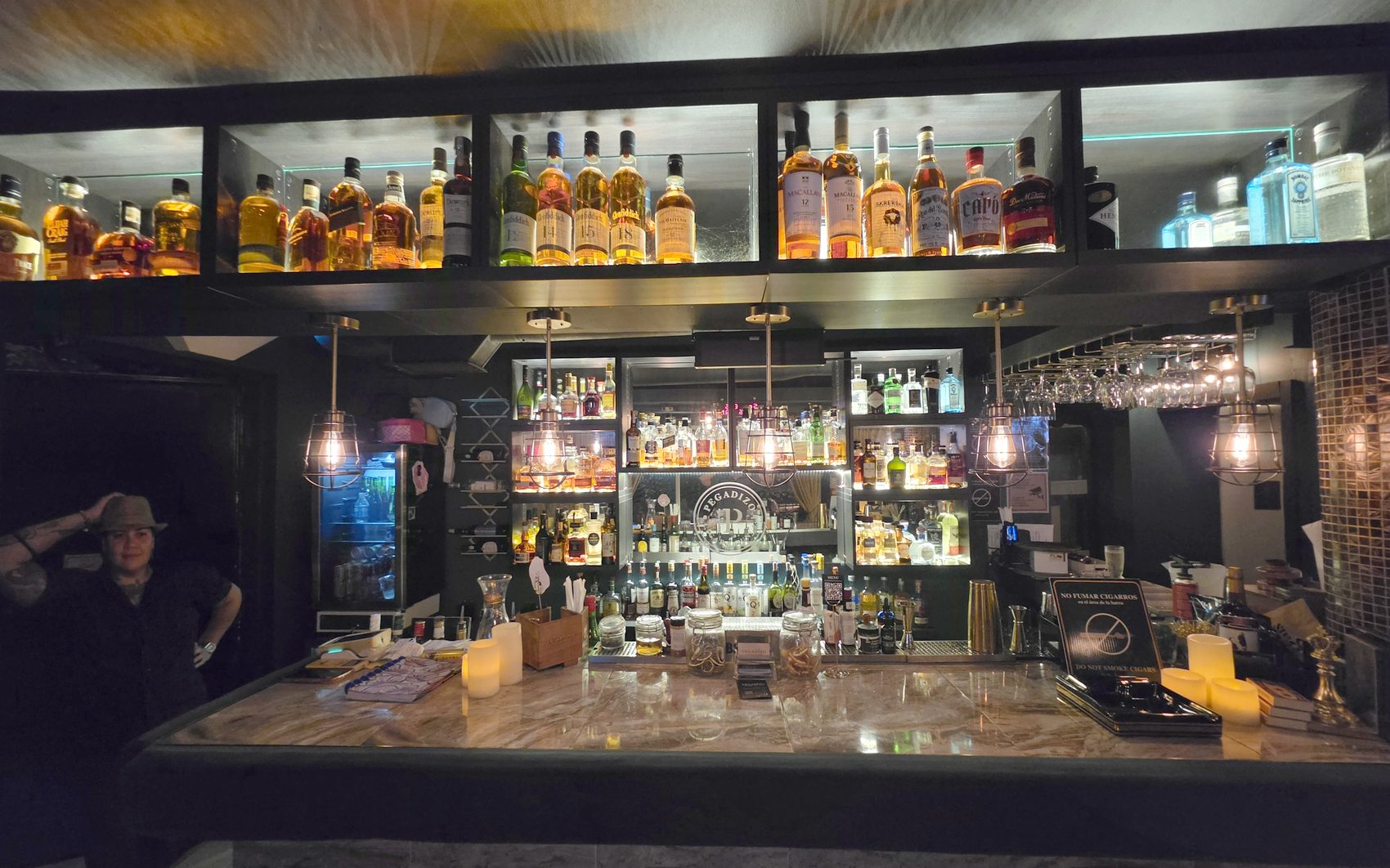 La barra de Pegadizo, con la estanteria de botellas iluminada y la barra de marmol