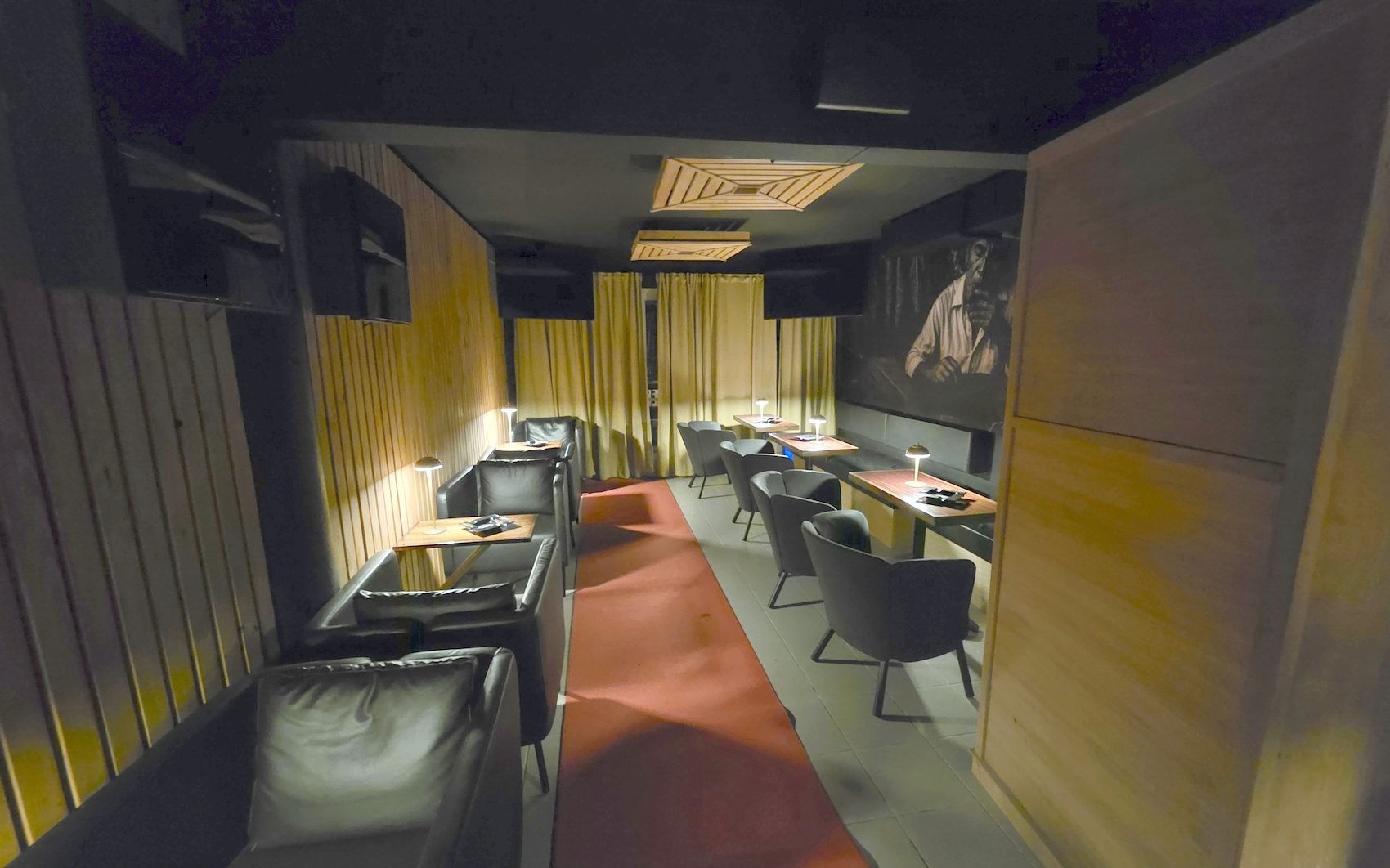 El speakeasy privado de Pegadizo, con alfombra roja, butacas y mesas de madera