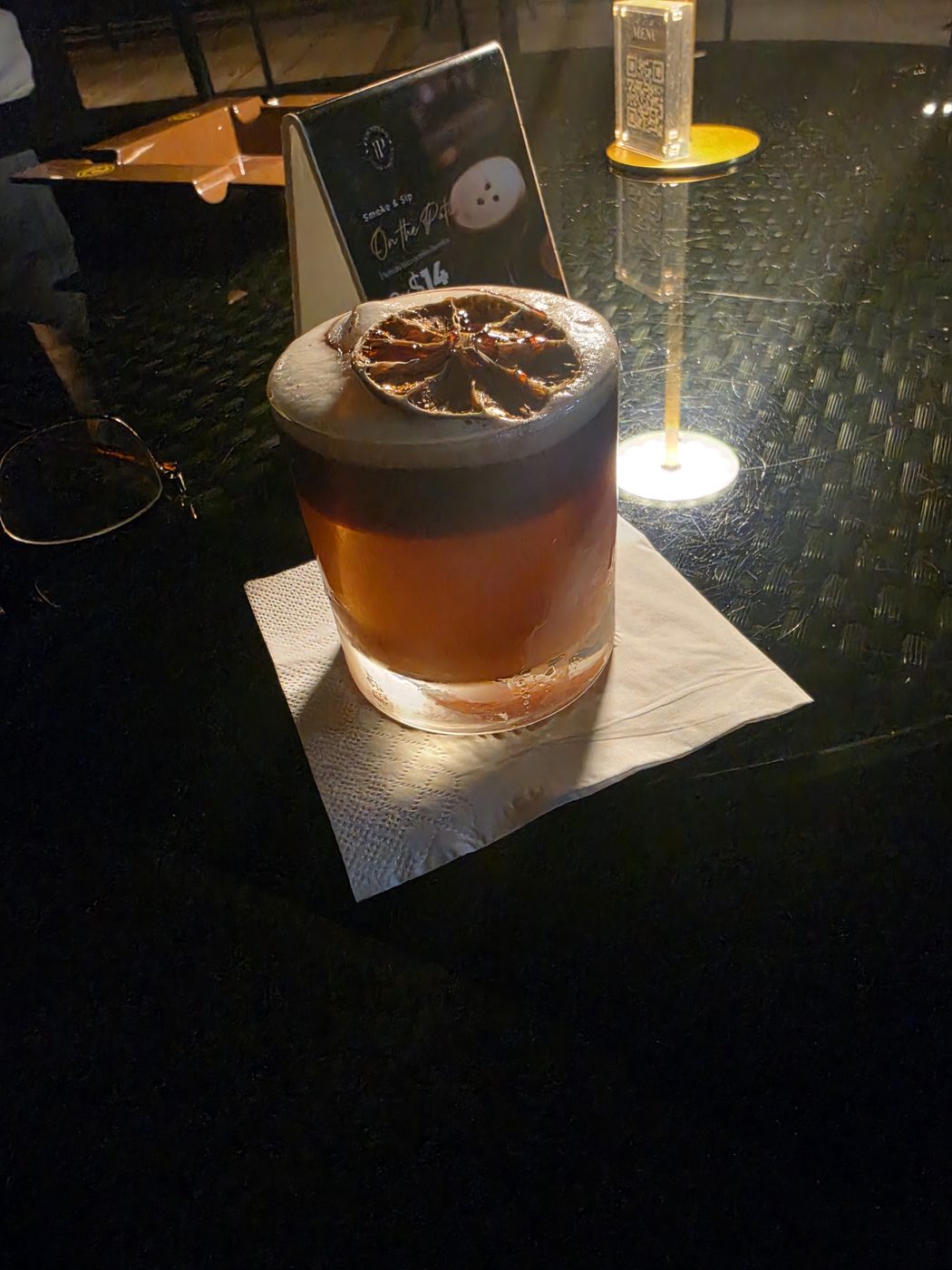Un cóctel servido en vaso bajo con una rueda de cítrico deshidratado