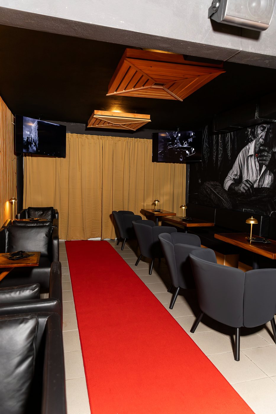 La alfombra roja del speakeasy, con el sofa de cuero y las mesas de madera