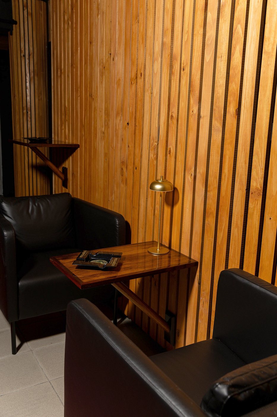 El rincon de listones de cedro del speakeasy, con el sofa de cuero y la mesa